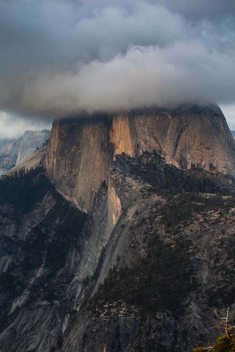 Half Dome sitting among the clouds around sunset