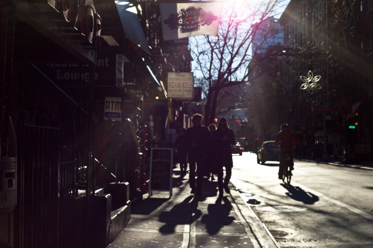 Backlit pedestrians and strong flare present. New York City, New York.