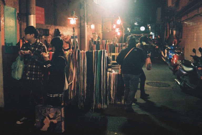 Very poorly lit scene of a shoelace and repair vendor  (Canon Canonet QL17 with Fujifilm X-TRA 400)